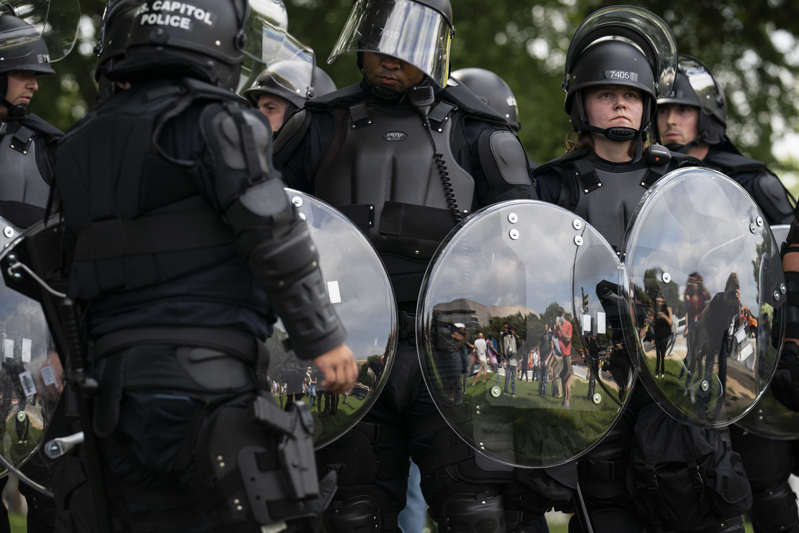 a group of people in uniform: Officers stand by in body armor during the Justice for J6 rally at the Capitol on Saturday. (Photo by Jabin Botsford/The Washington Post)