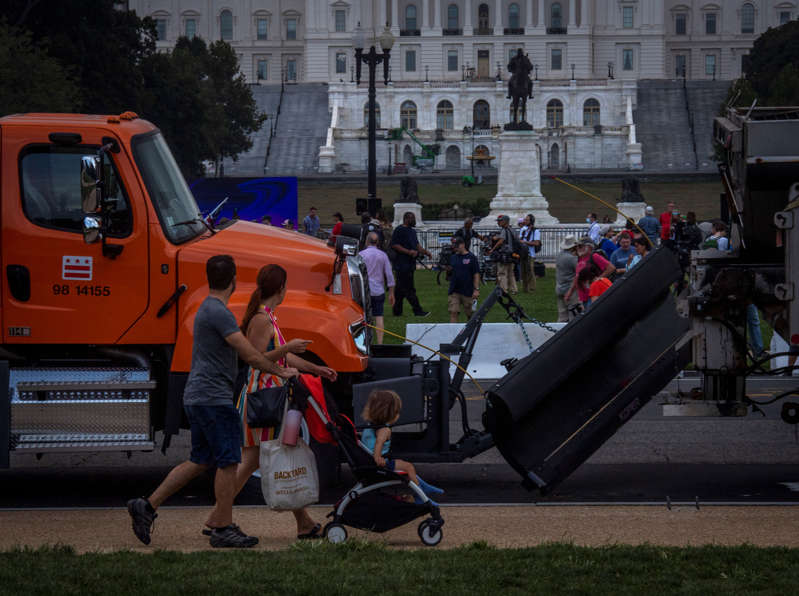 a truck is parked in front of a building: Mall visitors get a view of the protest area through a gap in a line of big trucks parked end to end as enhanced security around the Capitol for the Justice for J-6 protest rally. (Photo by Bill O'Leary/The Washington Post)